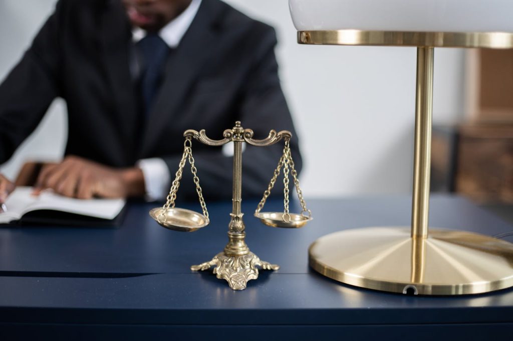 a-balance-scale-on-a-table-6077861 Elegant legal office with a close-up of golden scales of justice on a sleek dark desk.