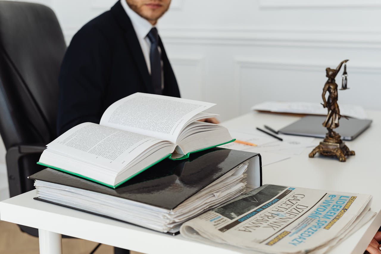 creative-02 A lawyer sitting at a desk with legal books, documents, and a newspaper, embodying professionalism.