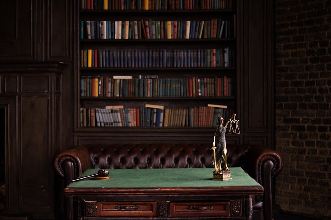 creative-03 A classic study room with shelves of books, a gavel, and Lady Justice figurine on a green table.