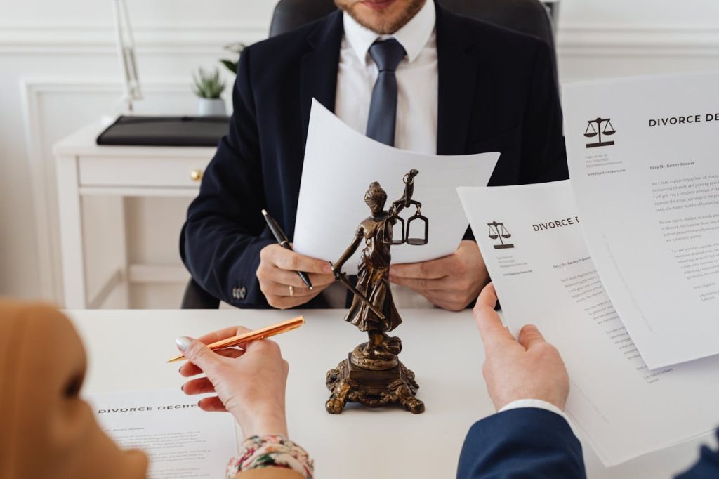 lawyers-looking-at-divorce-paper-7876050 Legal professionals reviewing divorce documents in a law office with a Lady Justice statue.