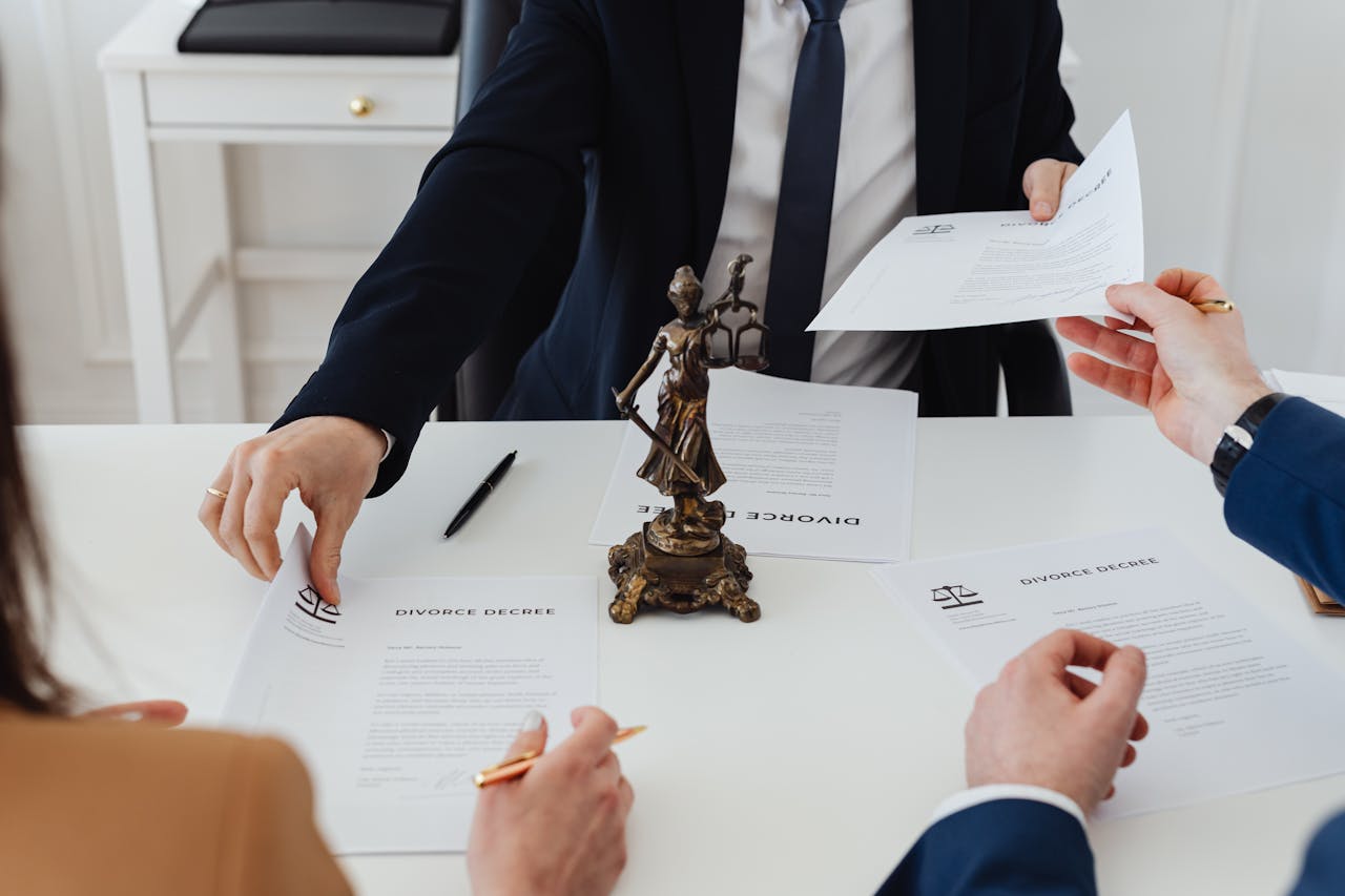 digital-01 Three adults discussing divorce documents in a formal office setting with legal statue in view.